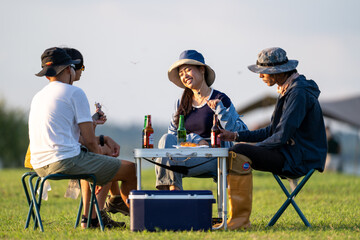 Three people are sitting around a picnic table with drinks and food