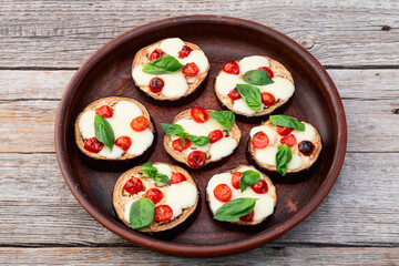 Italian mini pizza . Aubergine (eggplant ) with mozzarella cheese and basil . On rustic background