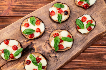 Italian mini pizza . Aubergine (eggplant ) with mozzarella cheese and basil . On rustic background