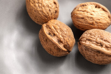 Unshelled whole rough walnuts in a kitchen ceramic plate with uneven rustic design. Organic nuts. Top view. Close up