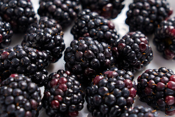Ripe blackberries on white plate. Fresh organic bramble berries close up