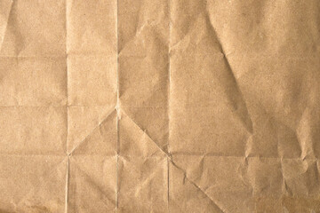 Brown old crumpled sheet of paper with straight geometric folds and wrinkles forming a natural grunge pattern. Abstract rough background