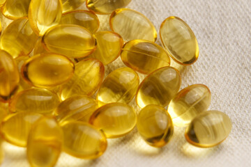 Golden soft gel capsules on a textile background. Nutritious diet vitamin pills