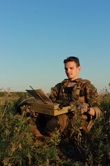 A war correspondent works in the field. citizen journalist with a typewriter. man in military uniform in the forest