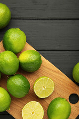 Green lime with cut in half on cutting board on black background. Vertical photo
