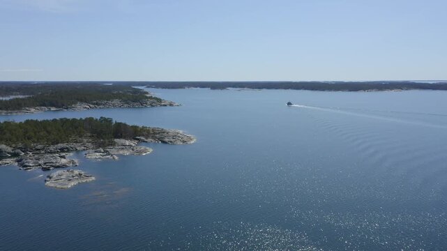 Small tugboat making way ahead in Finnish archipelago fairway. Wide aerial chasing view.