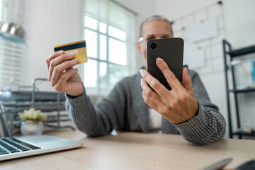 Person Using Credit Card for Online Payment on Smartphone at Home Office Desk