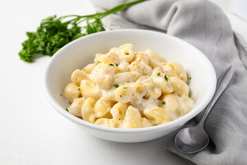 Macaroni cheese in bowl with spoon on white background