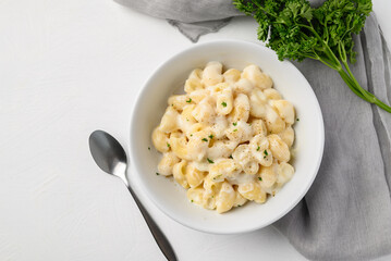Macaroni cheese in bowl with spoon on white background, Top view