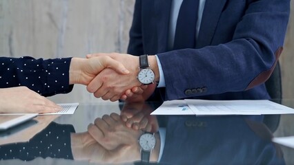 Professional handshake between two professionals and applauds at a corporate meeting with reflection on table over a business meeting. Business people concept