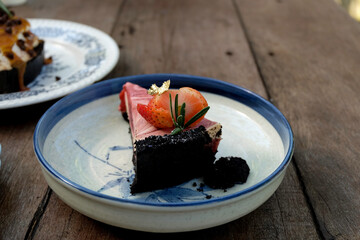 Strawberry cake topping with fresh strawberry and strawberry cream in ceramic dish on wooden table closed up selective focus blur background, bakery concept