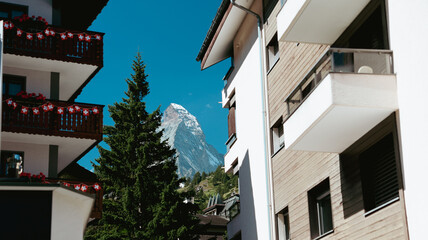 Matterhorn mountain peak overlooking Zermatt buildings and trees under a clear blue sky