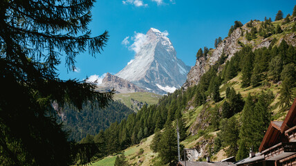 Majestic Matterhorn Mountain towering over Zermatt with lush greenery and alpine trees on a sunny...