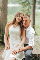 Fototapeta premium A young couple is sitting on a log in a forest
