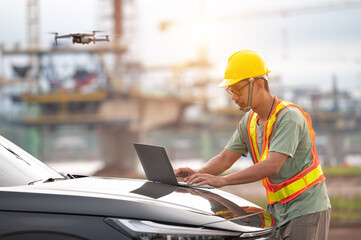Asian engineers inspect a construction project of a Thailand-Laos Mekong River bridge using a drone to get an aerial view of the bridge.