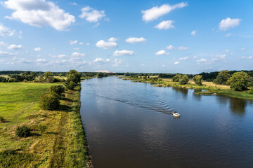 Tranquil river landscape with boat, lush greenery, and blue sky