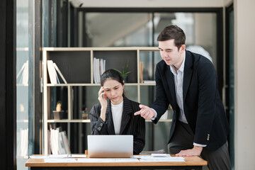 A man and a woman are sitting at a desk with a laptop