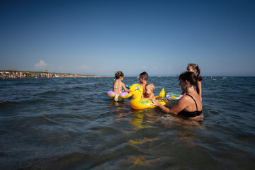 Obraz premium Family enjoying summer vacation at the beach with kids playing in the sea