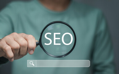 Businessman using magnifying glass focus to SEO icon to analyze SEO search engine optimization for...