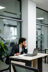 Modern office: Businessman working on his laptop, managing an e-commerce project. Ideal for showcasing a successful startup and digital entrepreneurship.