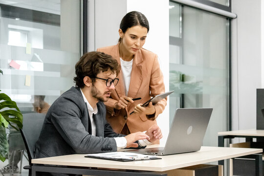 CEO mentoring a trainee on financial operations using a laptop in a modern office. A great shot for showcasing professional guidance and corporate training