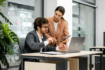 CEO mentoring a trainee on financial operations using a laptop in a modern office. A great shot for...