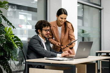 CEO mentoring a trainee on financial operations using a laptop in a modern office. A great shot for...