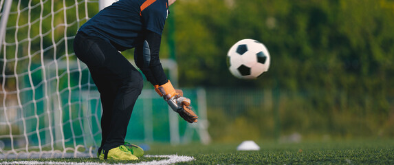 Soccer goalkeeper in gloves with a soccer ball in motion. Football training for young goalies
