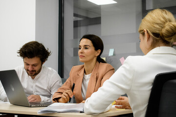 Fototapeta premium Employees participating in a brainstorming session in an office conference room. A perfect shot to illustrate a dynamic and creative work environment