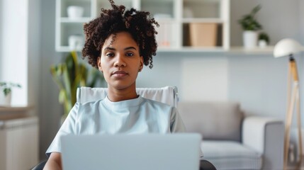 Home based remote therapy guidance session taking place on comfortable living room couch with young adult woman using laptop computer for online healthcare support and rehabilitation
