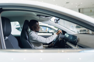 Smiling hipster African American businessman drives car, enjoy behind wheel