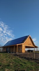 The wooden barn with solar panels stands in a peaceful pasture as cows graze under a bright sky