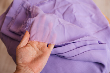 Light purple textile in hand, showcasing its smooth and airy quality, perfect for sewing projects.