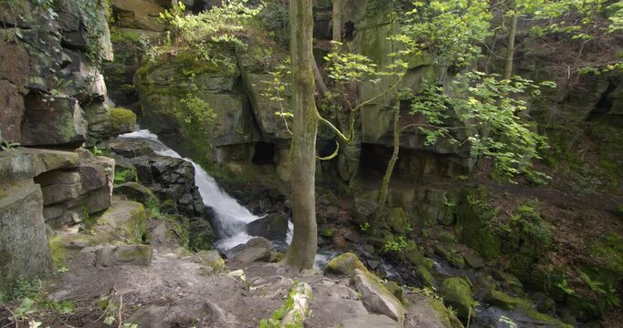 side on wide shot of the Lumsdale waterfalls with rocks and trees in foreground at Lumsdale, Matlock