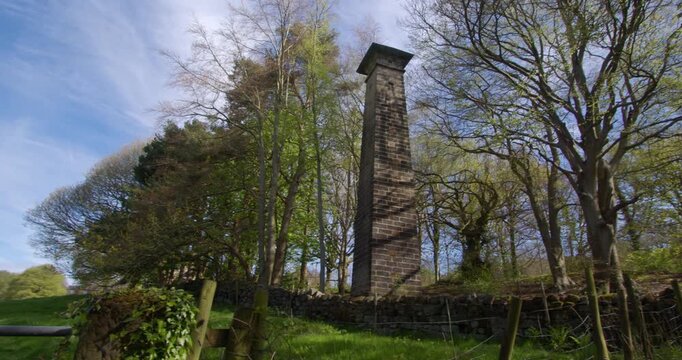 Panning wide shot of a disused brick chimney at Lumsdale waterfalls, Matlock