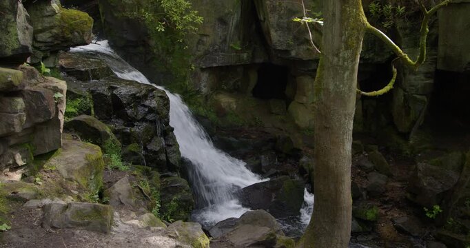side on wide shot of the Lumsdale waterfalls with rocks and trees in foreground at Lumsdale, Matlock