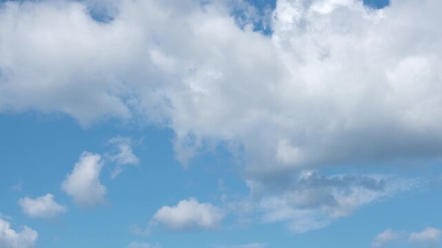 Time lapse of white fluffy disappearing clouds moving in the blue sky. Natural background, 4K resolution.