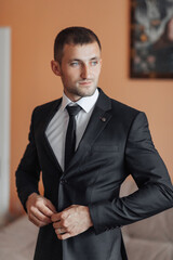 A man in a suit and tie is standing in front of a wall. He is wearing a tie and a suit jacket
