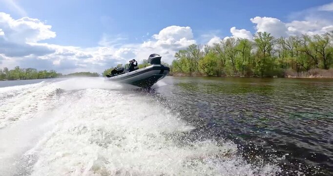A patrol boat floats along the river against the backdrop of beautiful clouds. The boat is patrolling the river. A fast patrol boat sails along the river.