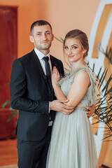 A man and a woman are posing for a picture. The man is wearing a suit and tie, and the woman is wearing a dress. They are both smiling and seem happy. Concept of love and happiness