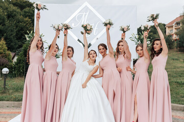 A group of women in pink dresses are posing for a picture with a bride in the center. The bride is...