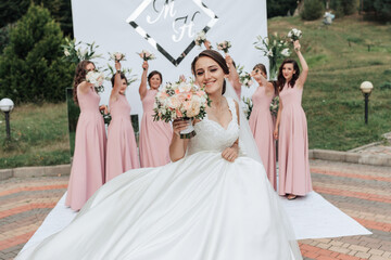 A bride and her bridesmaids are posing for a picture in front of a white wall