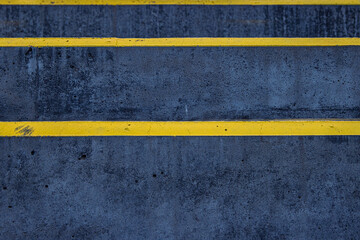 Closeup of a textured asphalt road with weathered yellow stripes on a rough gray pavement, great for use in street photography, urban design, or traffic-related visuals. Copy space
