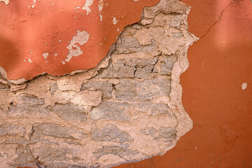 Cracked wall with rustic charm. A detailed close-up of a weathered wall with peeling red paint,...