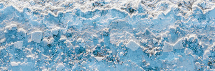 Top view of the icy shore. Winter aerial photograph of ice floes on the coast. Nature of the Extreme North. Cold frosty winter weather. Harsh arctic climate. Wide panorama. Natural background.