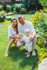 Fototapeta premium Mom and dad in nature with their one-year-old son. Happy family with little son in nature.