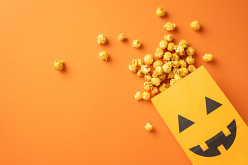 Popcorn spilling out of a pumpkin-themed bag on an orange background, symbolizing Halloween treats...