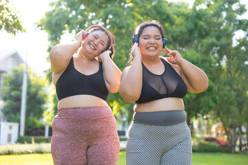 Fototapeta premium Dance, Listening music headphone. beautiful young chubby overweight woman in sportswear doing exercise outdoors at park. fitness sport club, body and health care. Activity