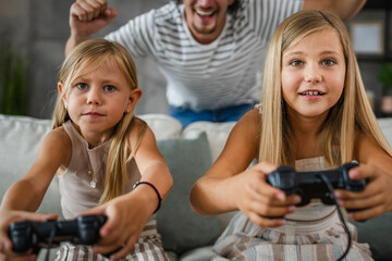 father cheer to his daughters while they play video games on joystick