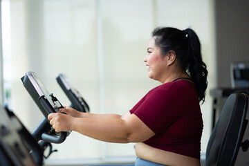 Fototapeta premium Exercise. beautiful young chubby overweight woman wearing sporty fitness clothes doing exercise indoors at gym fitness sport club, body and health care